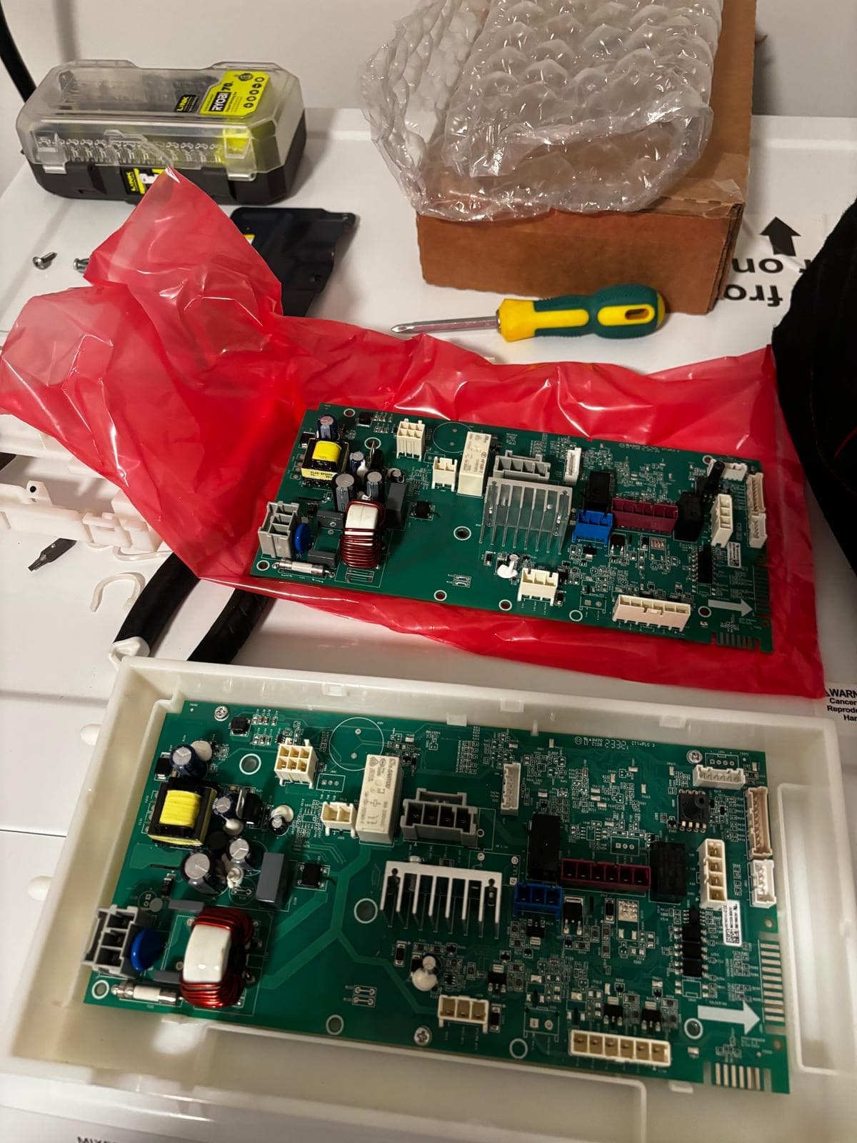 OEM appliance main control board replacement in Connecticut — new PCB unpacked from anti-static packaging next to old failed board before installation